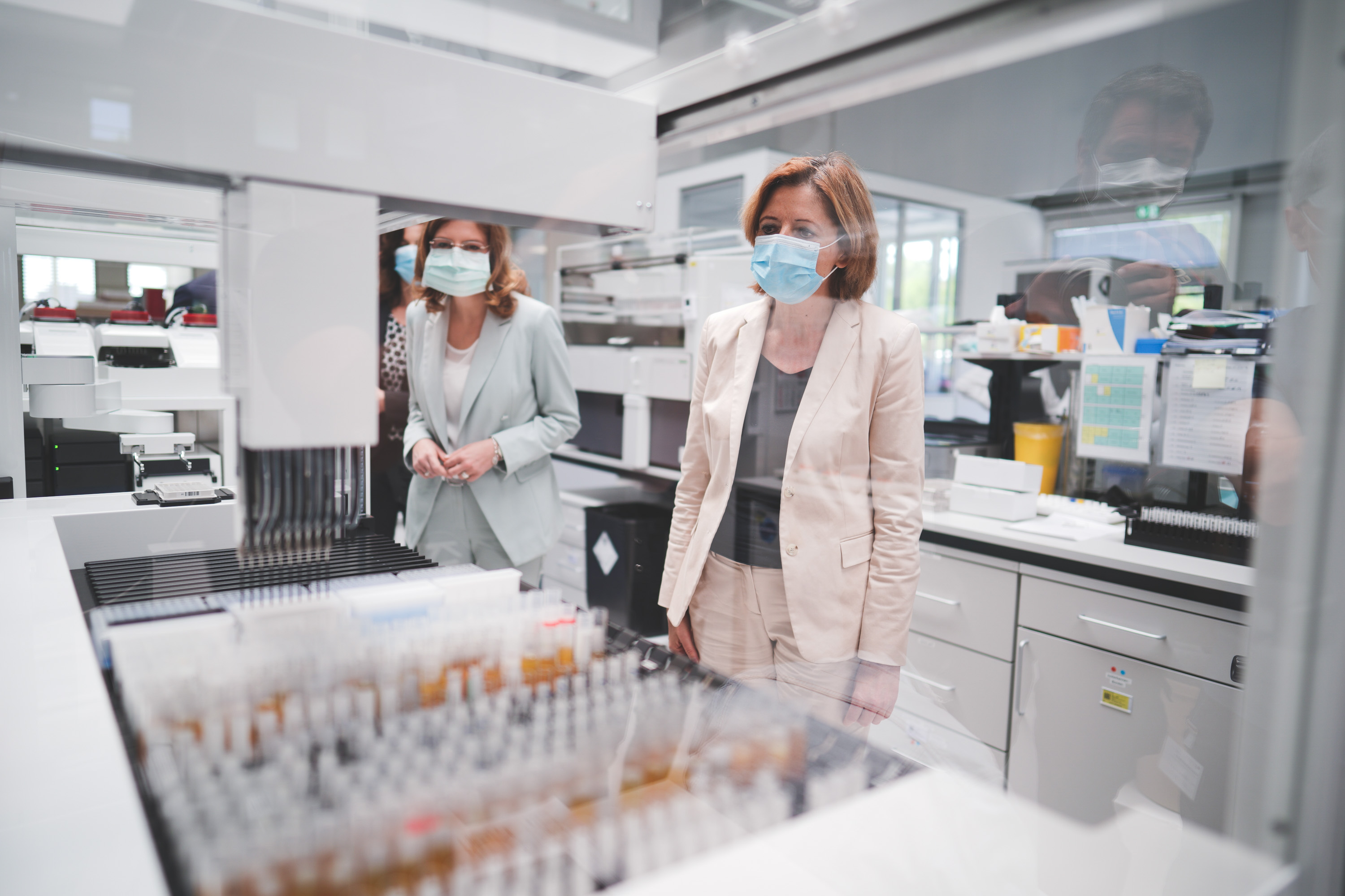 Ministerpräsidentin Malu Dreyer und Gesundheitsministerin Sabine Bätzing-Lichtenthäler beobachten die Bearbeitung der Serumproben in einem der neuen Geräte.